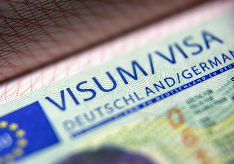 Visa stamp in passport close-up. German visitor visa at border control. Macro view of Schengen visa for tourism and travel in EU. Document for multiple entry. Legal immigration to Germany and Europe.